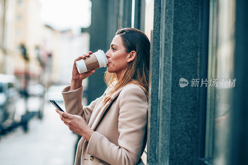 漂亮女人拿着智能手机喝着咖啡