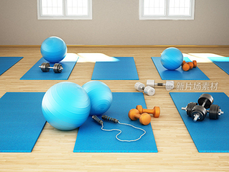 地板上放着普拉提垫、球、哑铃和其他健身器材