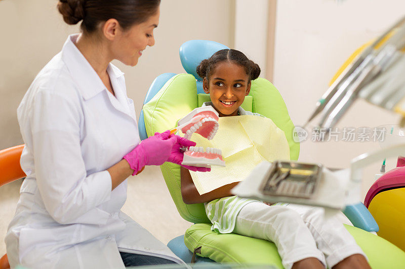 微笑的黑发女牙医使用牙科模型