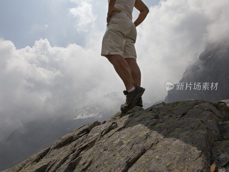 一个徒步旅行者站在云山的悬崖边