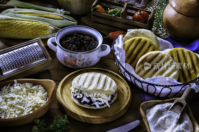 委内瑞拉传统食物，加碎奶酪和黑豆的Arepa(多米诺)。在乡村厨房的桌子上放着食材。