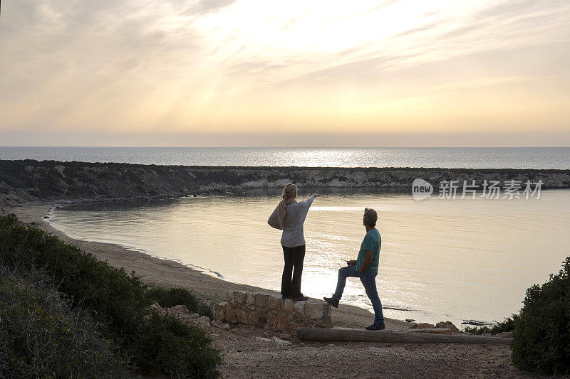 一对成熟的夫妇在平静的海湾里看日出