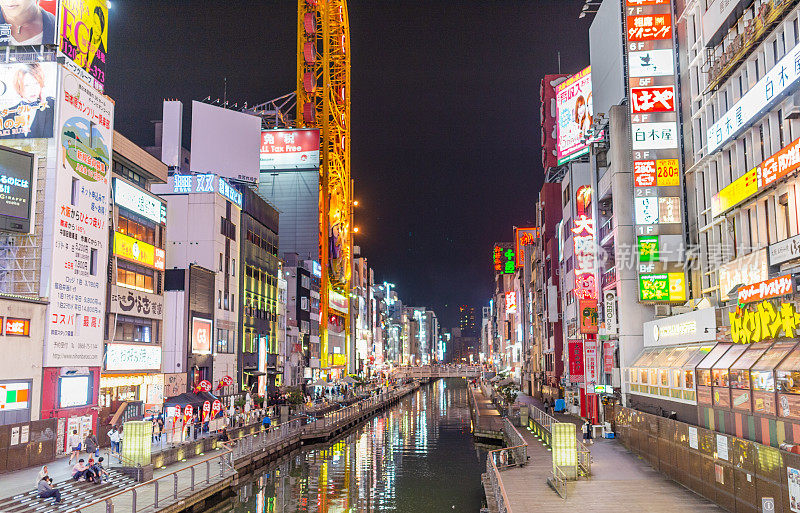 在日本大阪的道顿堀，五颜六色的广告牌照亮了大阪夜市周围的商店和零售店