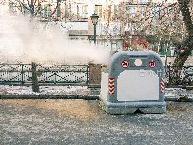 城市人行道上的灰色垃圾桶向空气中喷出烟雾