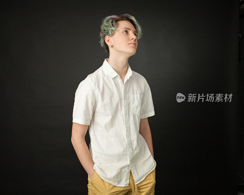 一个十几岁男孩的工作室肖像与绿色的头发在一个黑色的背景