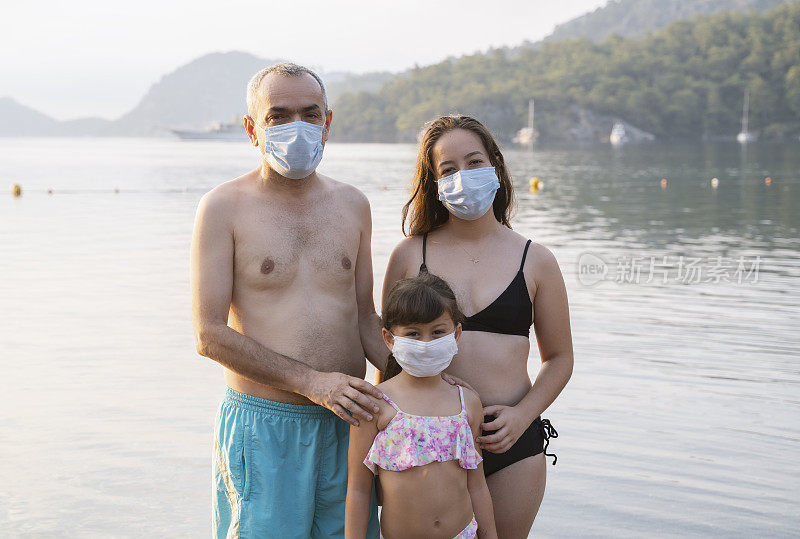 2019冠状病毒病大流行期间，家人带着医用口罩在海里游泳