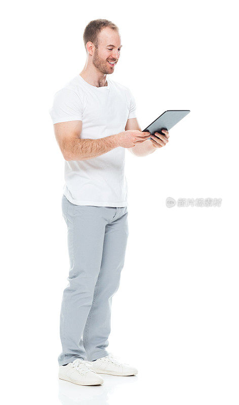 白人男性穿着裤子站在白色背景前使用触摸屏