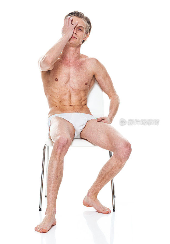 穿着泳裤在白色背景前休息的白人年轻男性