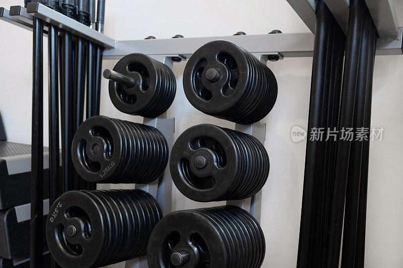 大群的各种重量板和杠铃悬挂在一个健身房