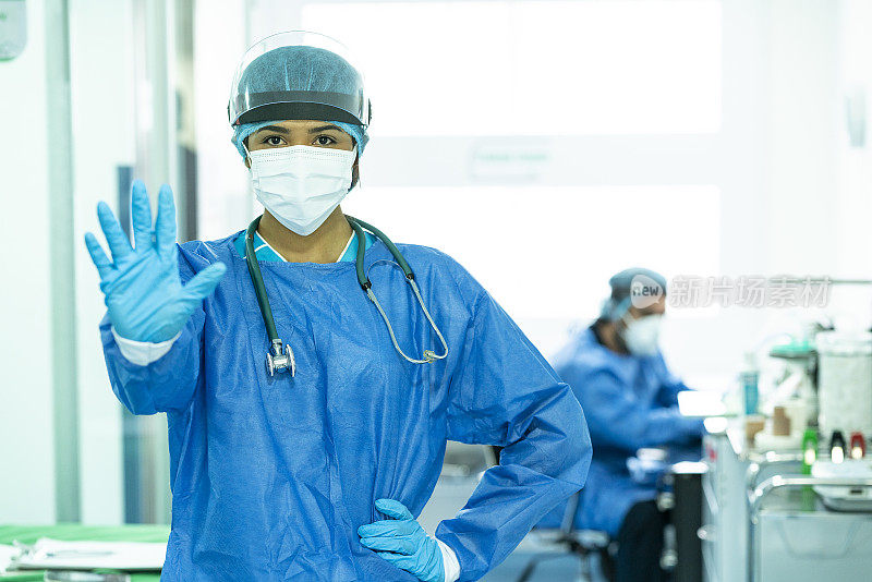 在重症监护室医院，身穿生物安全服的医生在镜头前用手指着手势