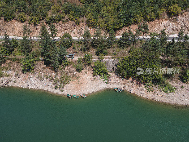 空中公路旅行在山附近的一个湖与船。忙碌的生活，俯视图，乡村道路经过旁边的山湖。