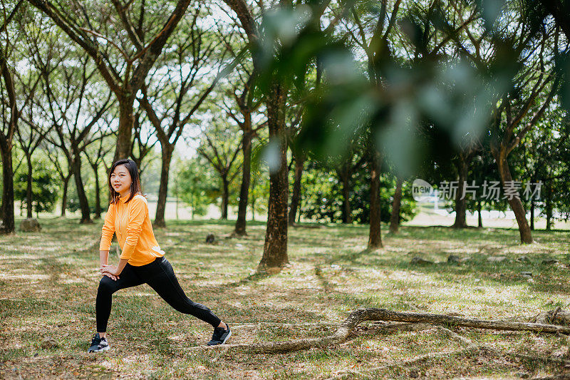 运动的亚洲华人妇女伸展她的腿和做热身运动