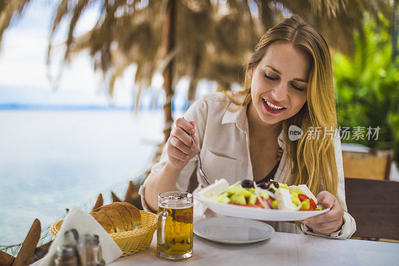 微笑的女人在户外餐厅吃希腊沙拉