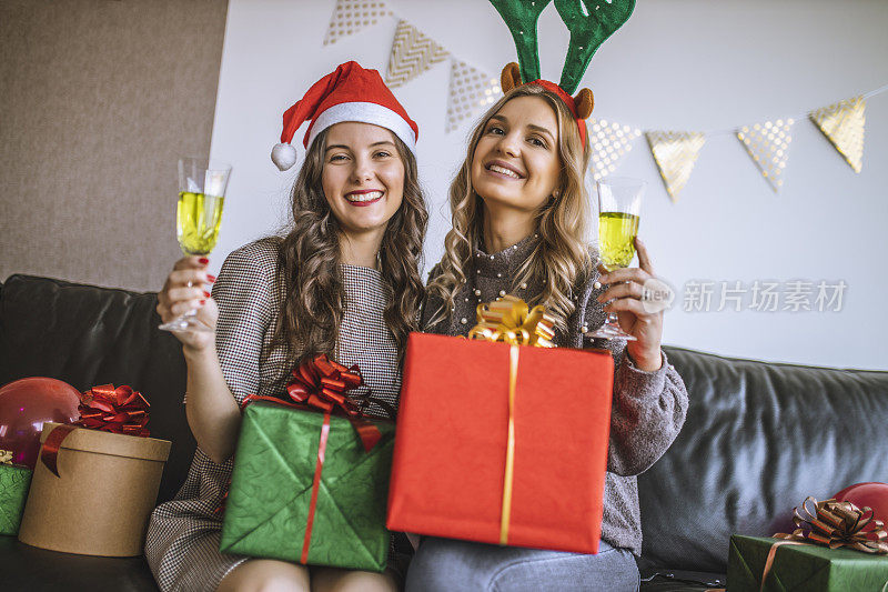 年轻的女性朋友们在家喝着香槟庆祝圣诞节