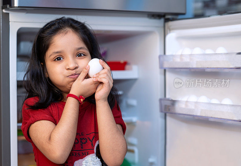 小女孩从冰箱里拣鸡蛋