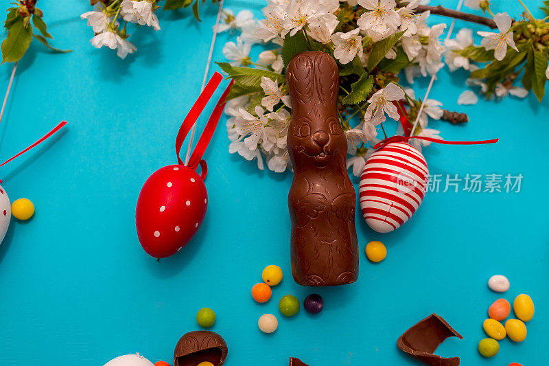 白色的木桌上放着复活节糖果。巧克力蛋，巧克力兔子和其他复活节糖果