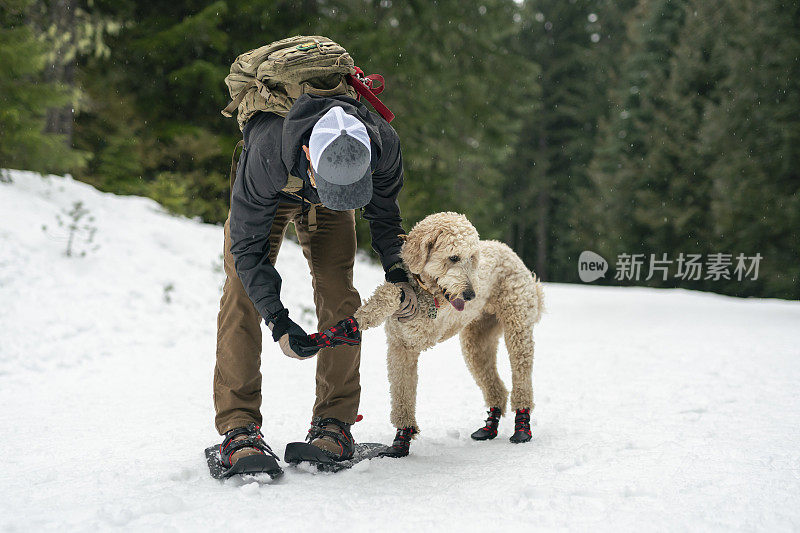 成年民族男子雪鞋与他的狗