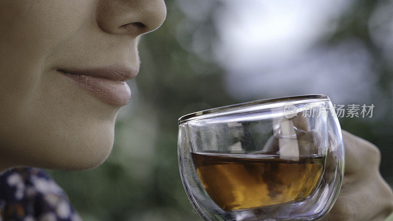 头部拍摄极端特写的西班牙裔年轻女子喝一杯芙蓉热茶在户外露台