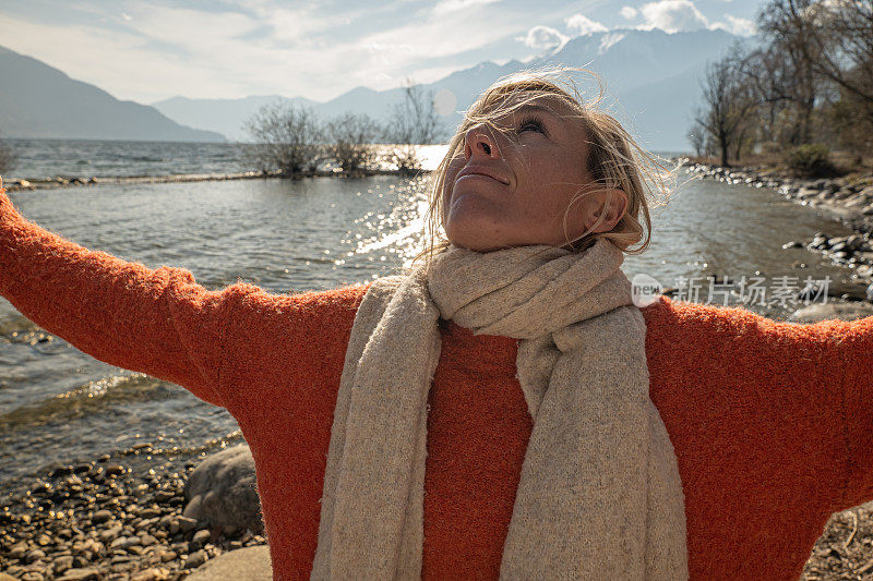 女人拥抱自然，她在提契诺的湖边伸出双臂