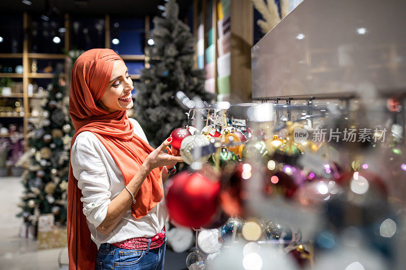 迷人的穆斯林女士拿装饰圣诞树