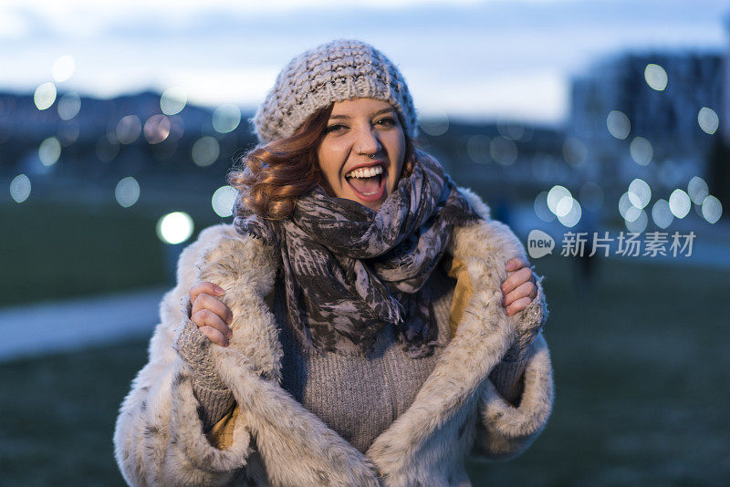 女人非常喜欢冬天的衣服在镜头前表演，背景是夜晚的灯泡。非常有表现力的快乐