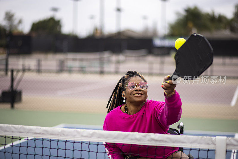 年轻的黑人残疾妇女在轮椅上与朋友玩皮球