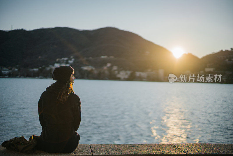 日出时分，年轻女子在湖边休息