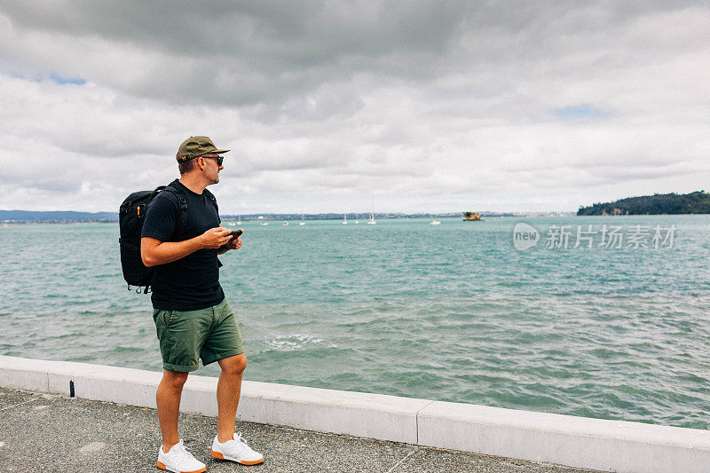 一名男子在海边用手机拍照