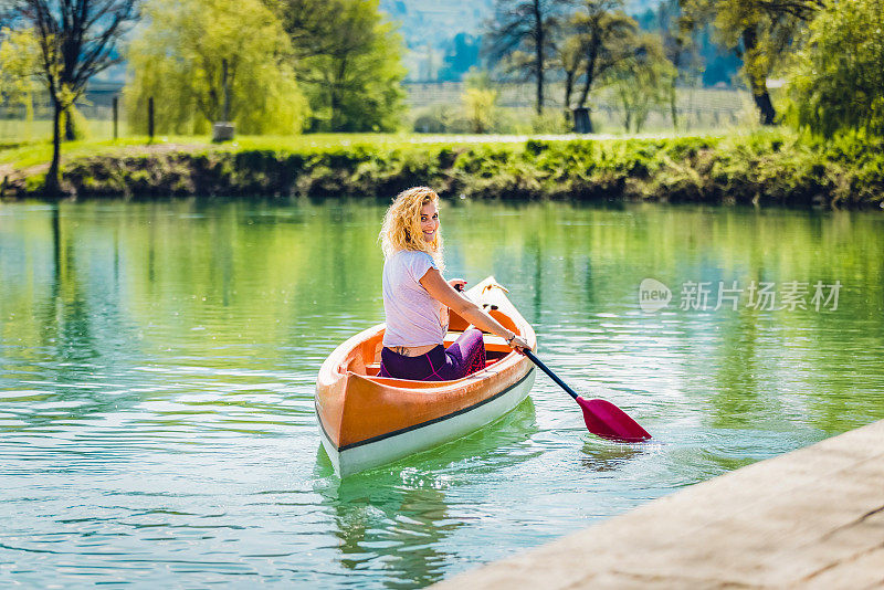 快乐美丽的女人在河边划独木舟