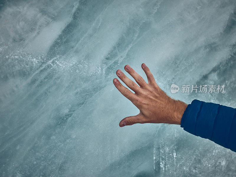 在冰川中，人类的手沿着冰墙滑动