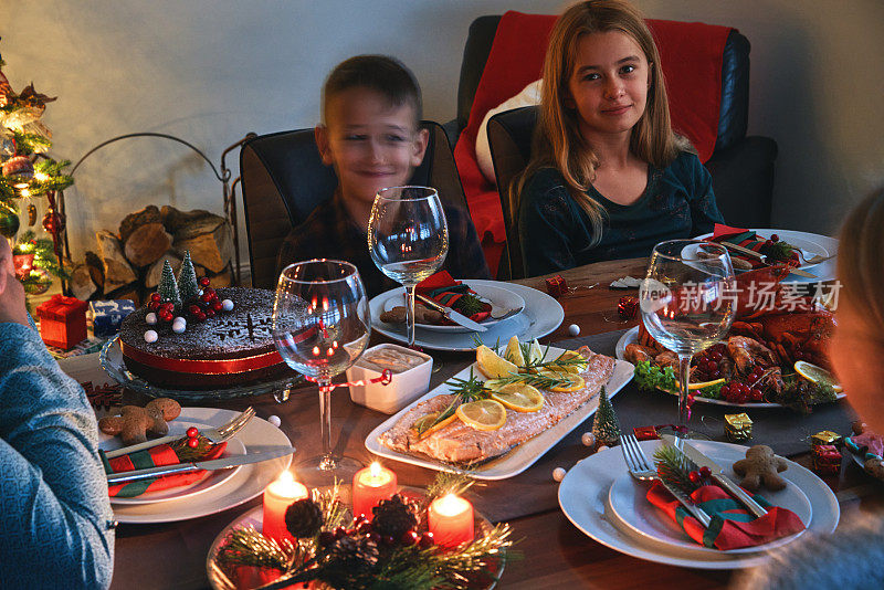 全家享用圣诞晚餐，有三文鱼片，扇贝，龙虾，虾和圣诞蛋糕
