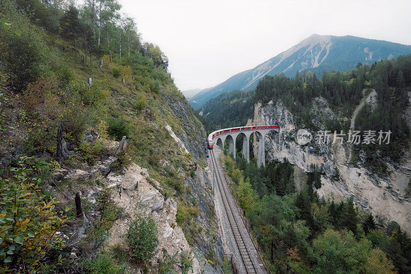 红色火车经过瑞士的Landwasserviadukt的高角度视图
