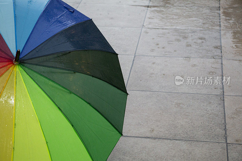 雨点落在彩虹伞上，天以自然为背景