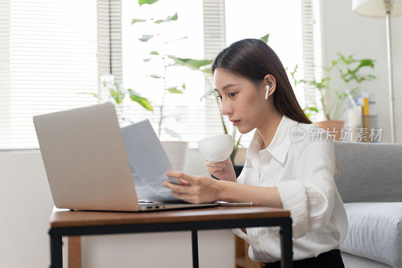 有吸引力的年轻女子使用笔记本电脑在家里工作。