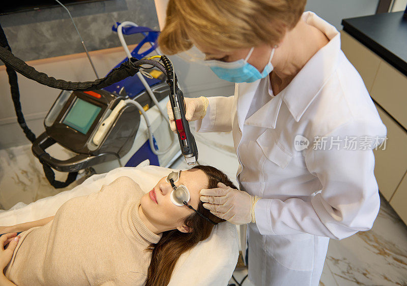 一名年轻女子接受面部激光美容治疗去除脸上的老化和色素斑。抗衰老过程。