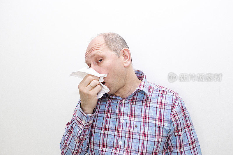 一个白种人生病了，流鼻涕。一个男人用纸巾擦鼻子。
