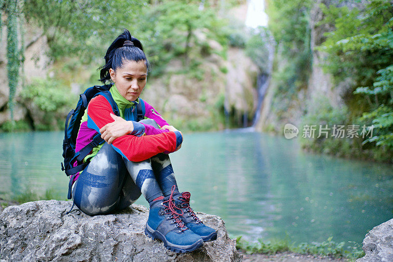 沮丧孤独的女人坐在瀑布前