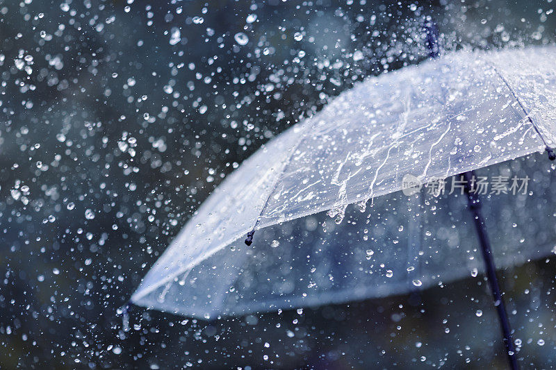 透明雨伞在大雨下抵挡水滴飞溅的背景。雨天的概念。