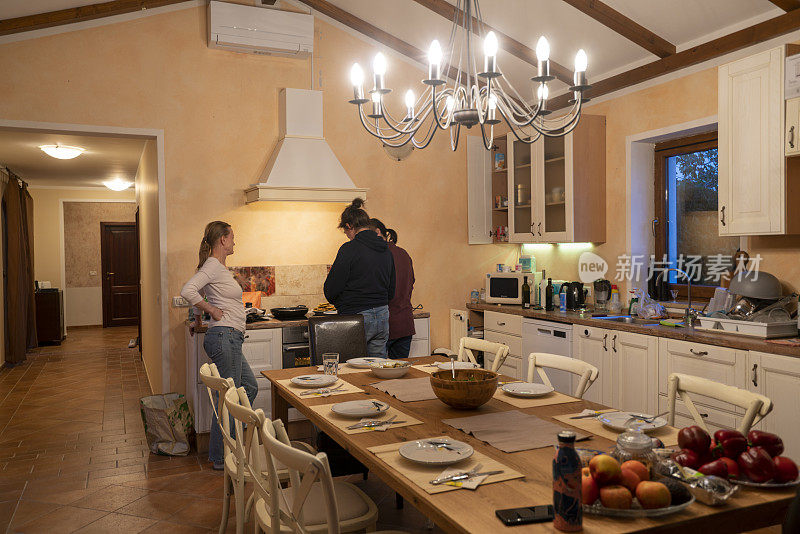三个女人在家里为朋友们准备餐桌和食物。
