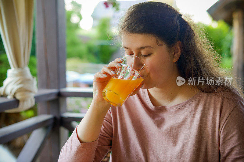 女人做新鲜的蔬菜沙拉，喝新鲜的橙汁