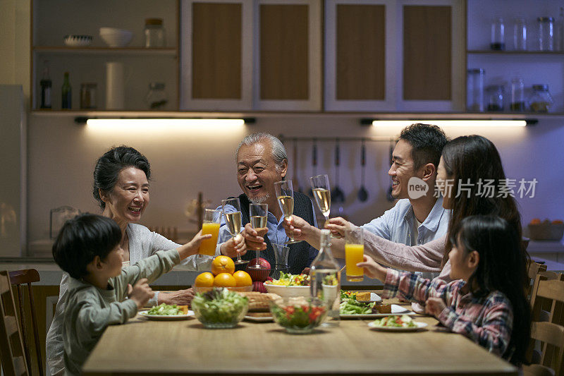 三代亚洲家庭在一起吃饭时敬酒