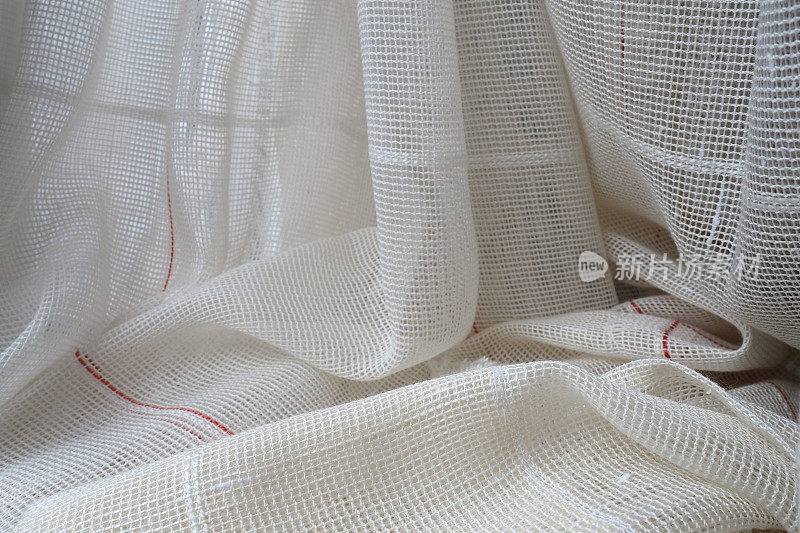 用细线编织而成的白色粗棉布或亚麻窗帘简单紧凑经济的公寓内部。房间里的窗户装饰。红色的条纹。