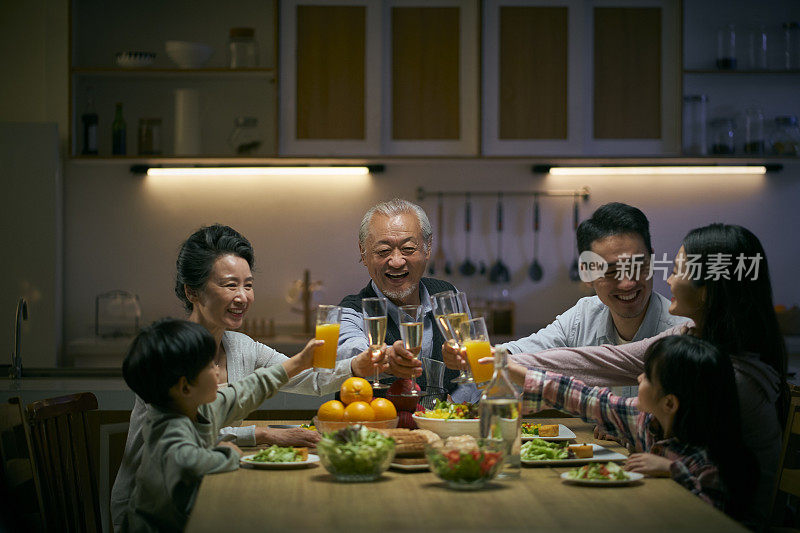 三代亚洲家庭在一起吃饭时敬酒