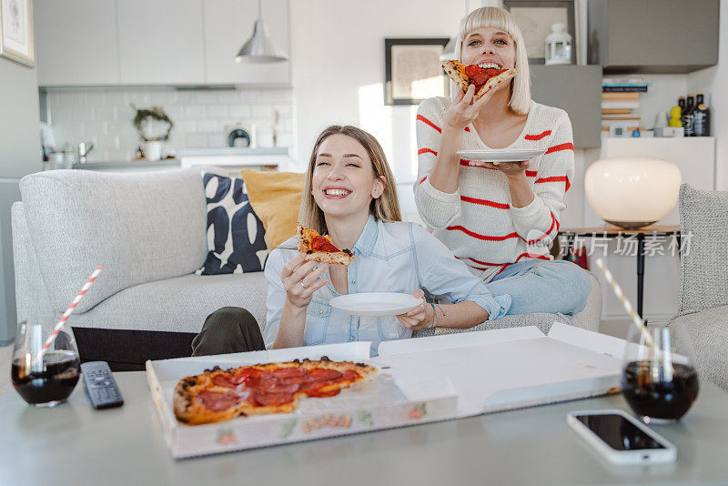 年轻女人在家里闲逛，享受披萨
