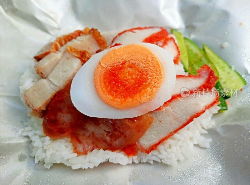 红烤猪肉配米饭和煮鸡蛋配食物包装纸-曼谷街头小吃。