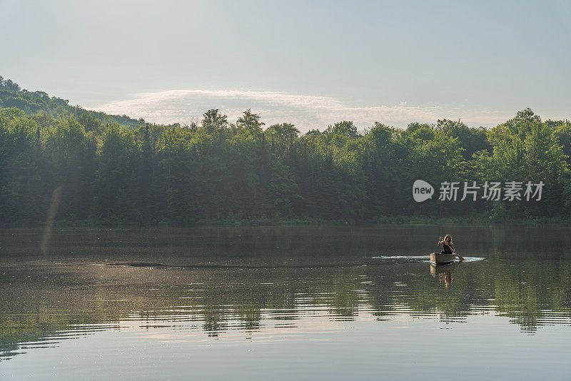 一个女人在清晨划独木舟。