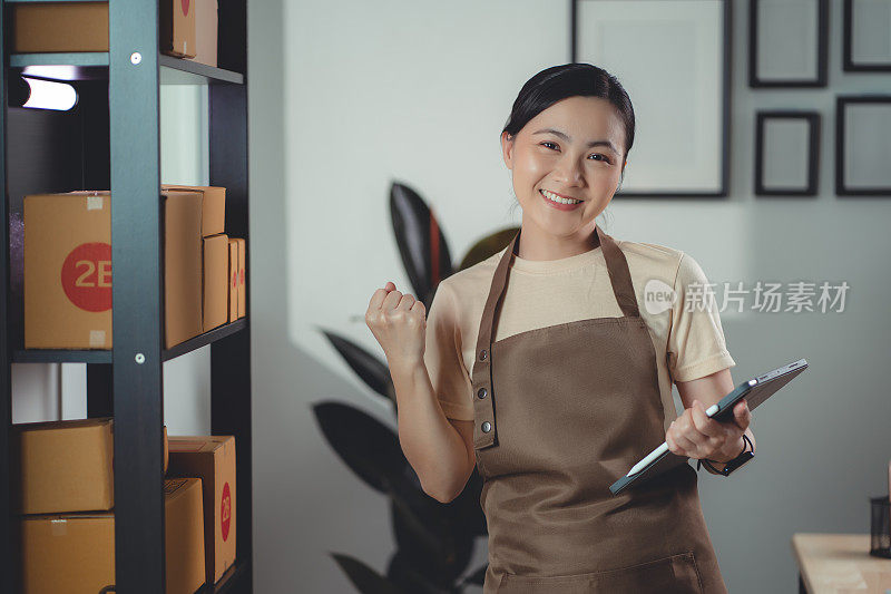 亚洲女网上卖家开心地微笑着拿着平板电脑看着摄像头。