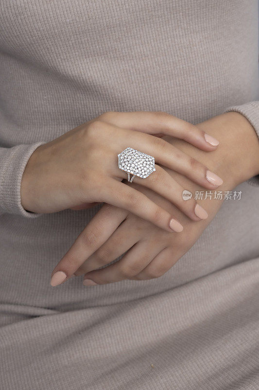 一个昂贵的白金刺绣戒指戴在女人的手指上。