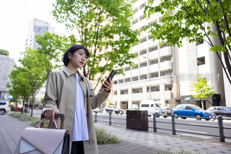 年轻的女商人在城市里使用智能手机