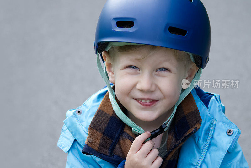 戴着自行车头盔的小男孩微笑着看着镜头